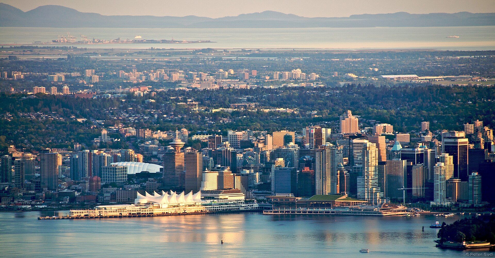 Vancouver at dusk seen from Grouse Mountain, the city glowing between forest and sea